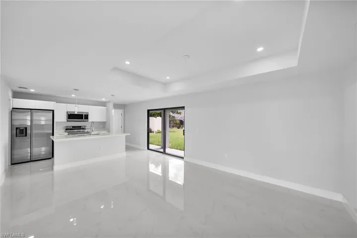 Unfurnished living room featuring sink, french doors, light tile flooring, and a raised ceiling