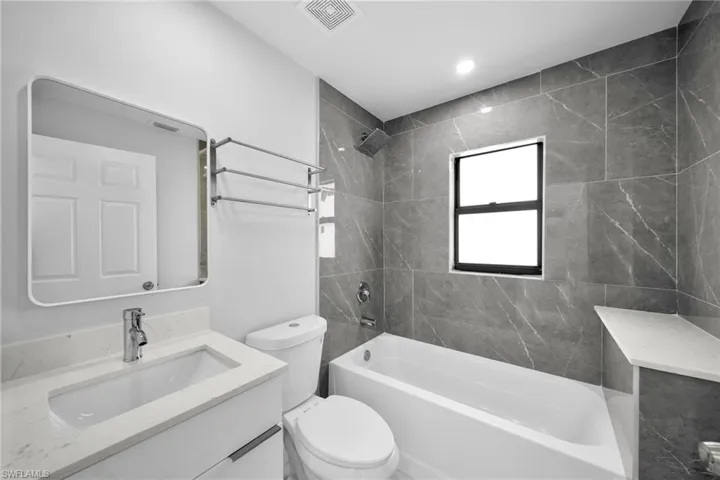 Full bathroom with vanity, toilet, and tiled shower / bath combo
