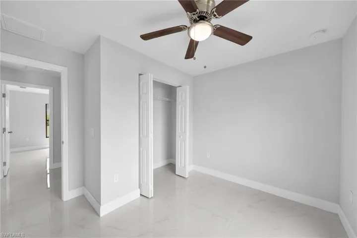 Unfurnished bedroom with a closet, ceiling fan, and light tile floors