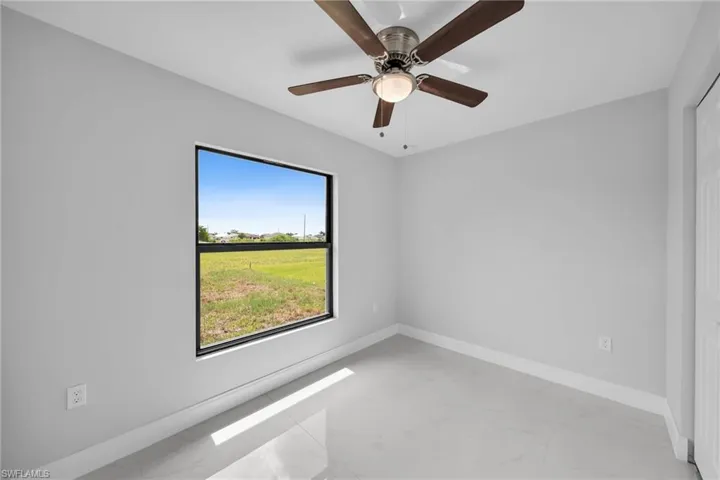 Tiled spare room featuring ceiling fan