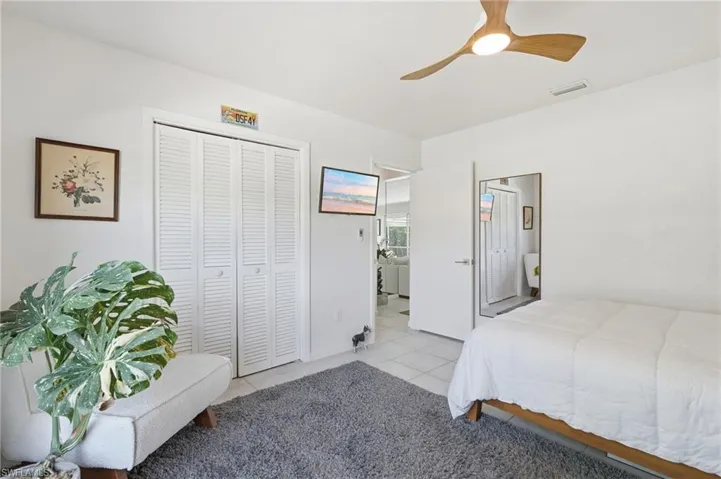 White interior with a modern ceiling fan, bi-fold louvered closet doors, and white tile flooring