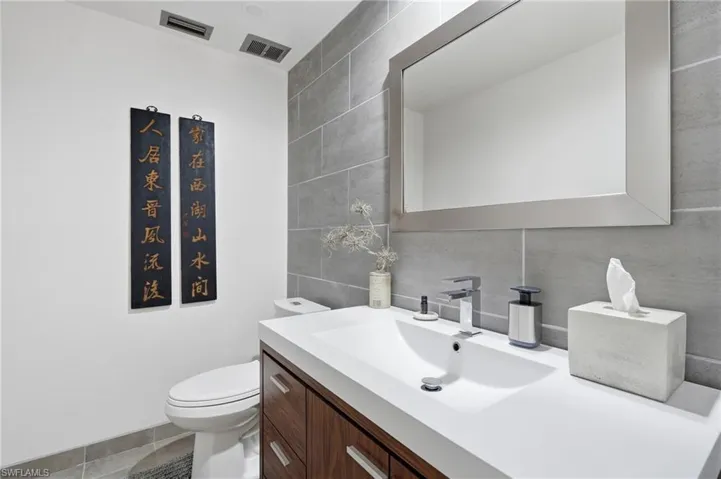 Modern bathroom featuring a wood-finish vanity with a white integrated sink, chrome faucet, and a large framed mirror