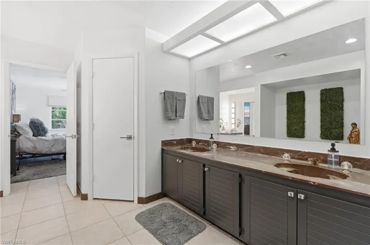 Bathroom featuring a dual vanity with undermount sinks, a large wall-mounted mirror, and recessed lighting