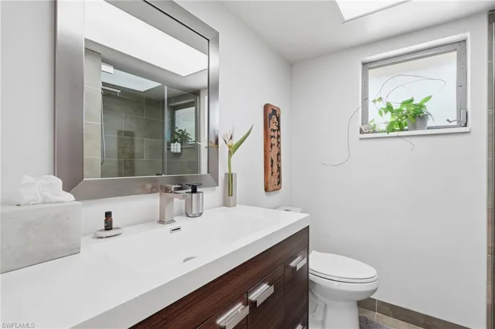 Contemporary vanity with a white countertop and integrated sink, brushed nickel faucet, and a large framed mirror