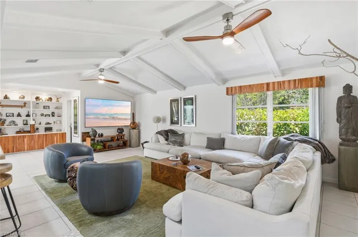 Living area featuring a vaulted ceiling with exposed beams and dual ceiling fans