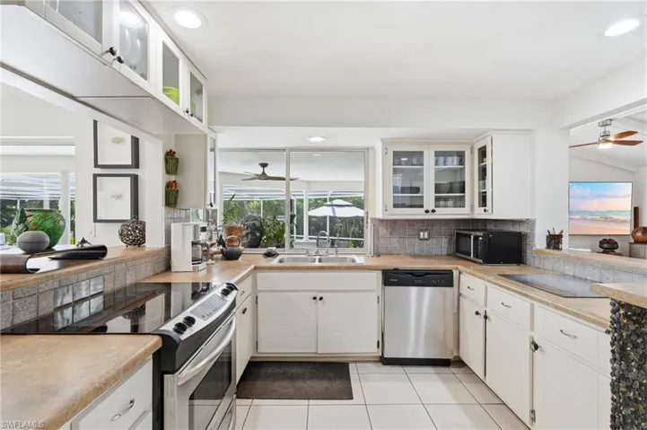 Kitchen featuring white cabinetry, light-toned countertops, a tile backsplash, stainless steel appliances, and tile flooring