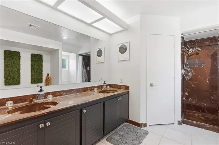 Dual vanity with brown marble-patterned countertops, integrated sinks, and dark cabinetry