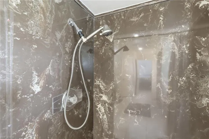 Shower enclosure featuring dark marbled walls with white veining
