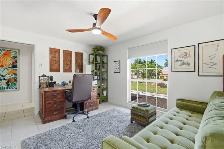 Bright room featuring a large window, tiled flooring, a ceiling fan with wooden blades, and white walls