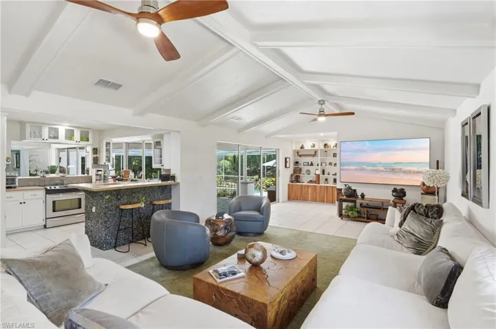 Vaulted ceilings with exposed beams and ceiling fans enhance this open-concept living space