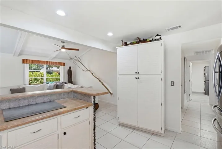 Kitchen area featuring white cabinetry, tile flooring, a built-in pantry, and a breakfast bar with a tile backsplash