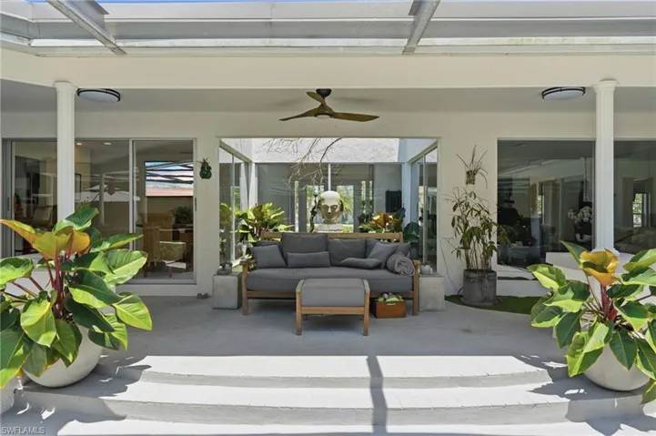 Spacious covered patio with light-toned flooring, featuring a ceiling fan and recessed lighting