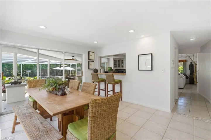 Dining area featuring large sliding glass doors, recessed lighting, a breakfast bar with built-in cabinetry, and neutral tile flooring
