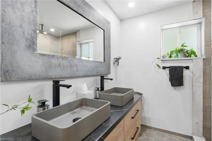 Dual vessel sinks with matte black fixtures, set on a dark countertop