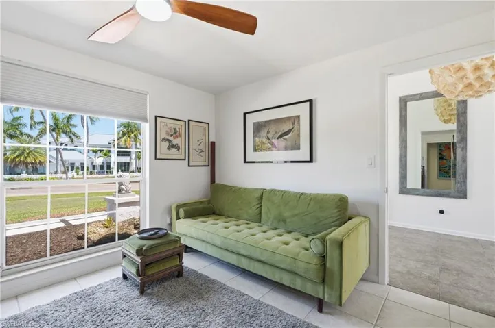 Bright interior space featuring a large multi-pane window with privacy blinds, a ceiling fan with wooden blades, and light-toned tile flooring
