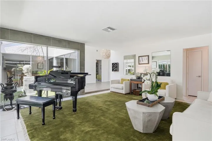 Expansive living area featuring a neutral color palette, recessed lighting, large format white floor tiles, and full-height windows