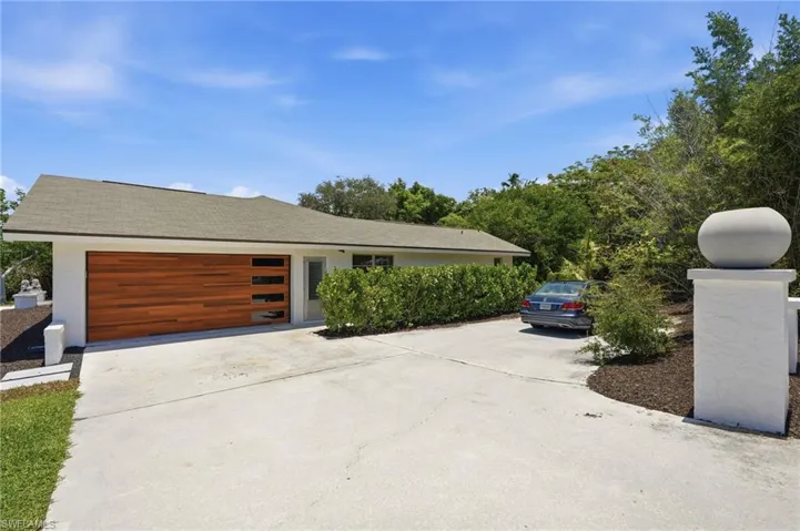Contemporary exterior featuring a wood-finish garage door with horizontal glass inserts, a white stucco finish, and a gray shingle roof