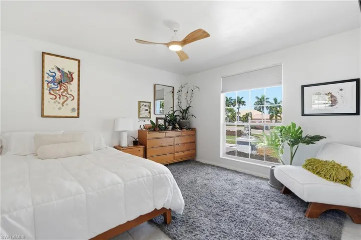 Bright bedroom space with a large window featuring grid panes and a roller shade