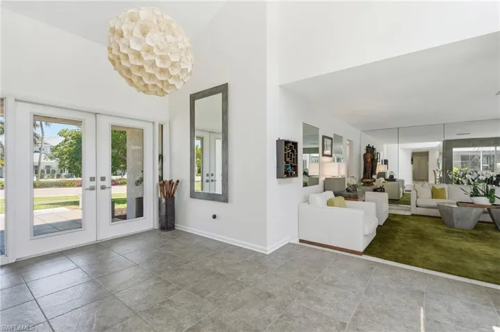 Grayscale tile flooring and white walls define this entry area, featuring a vaulted ceiling and a large, shell-patterned pendant light fixture
