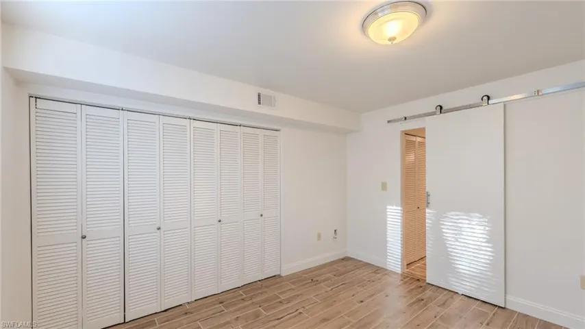 Unfurnished bedroom featuring wood tiled floors and a barn door