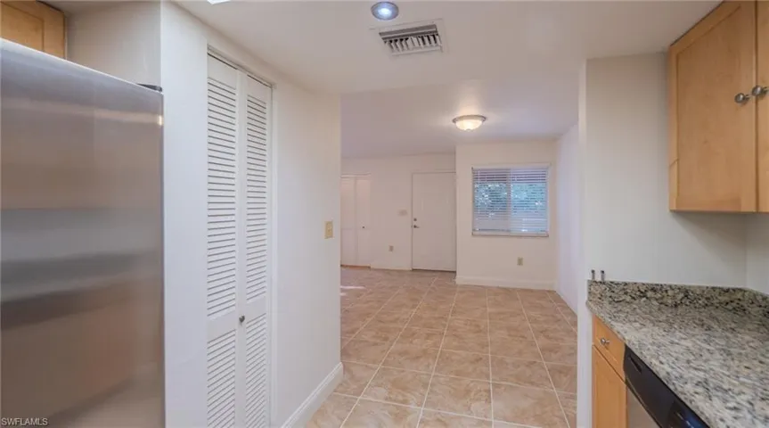 Kitchen featuring stainless steel appliances, light wood finish cabinetry, light stone counters, and light tile patterned floors