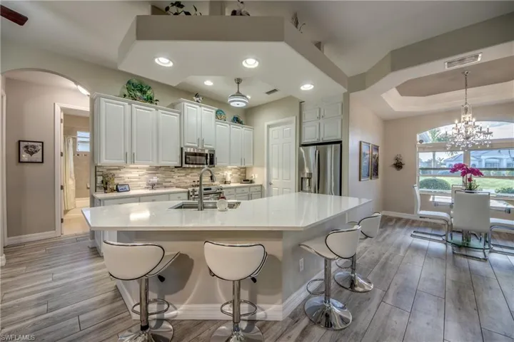 Kitchen with light hardwood / wood-style flooring, white cabinets, a center island with sink, and appliances with stainless steel finishes
