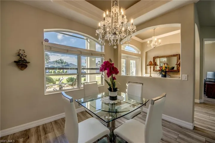 Dining space with french doors, an inviting chandelier, ornamental molding, and hardwood / wood-style flooring