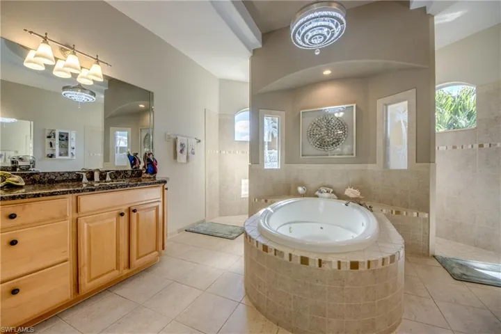 Bathroom featuring tile patterned flooring, vanity, and shower with separate bathtub