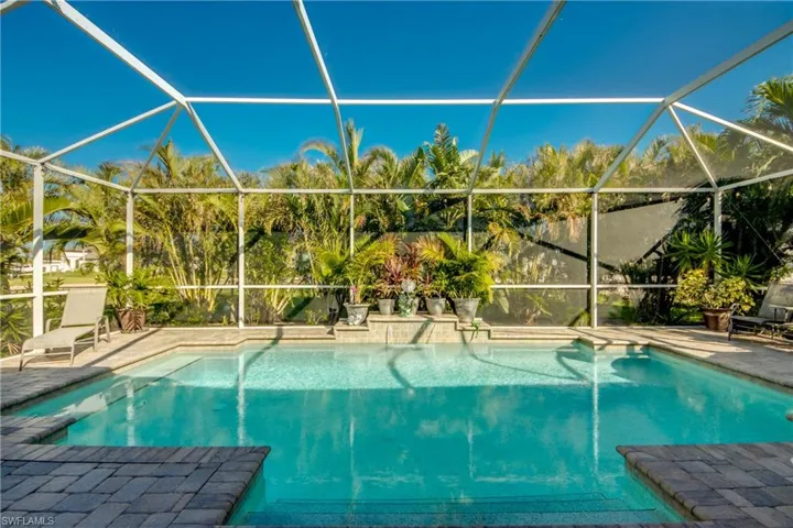 View of swimming pool featuring glass enclosure and a patio