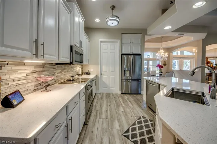 Kitchen featuring light stone countertops, appliances with stainless steel finishes, tasteful backsplash, sink, and light hardwood / wood-style flooring