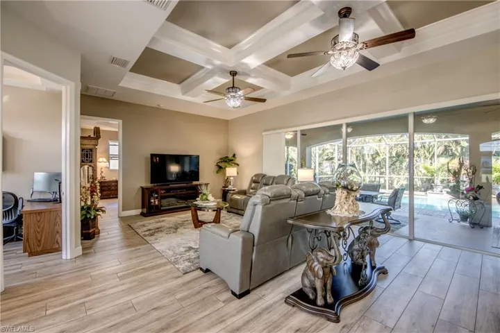 Living room with beamed ceiling, light hardwood / wood-style floors, ceiling fan, and coffered ceiling