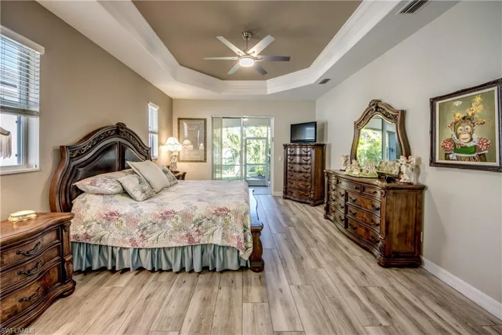 Bedroom featuring access to exterior, ornamental molding, a tray ceiling, ceiling fan, and light hardwood / wood-style floors