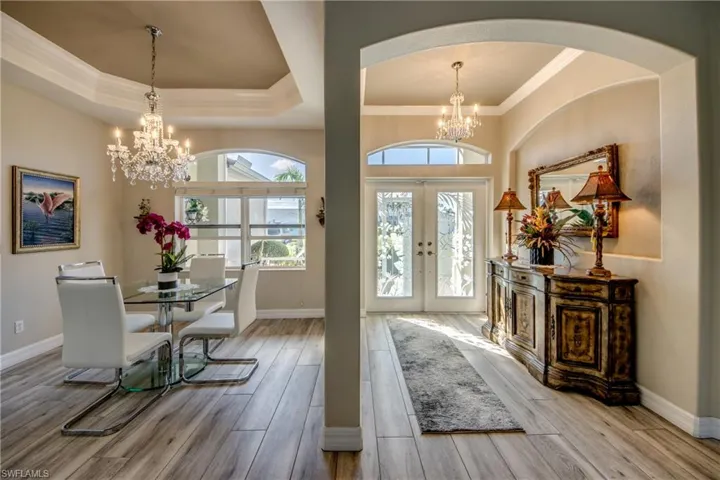 Entryway with french doors, a tray ceiling, crown molding, light hardwood / wood-style flooring, and a chandelier