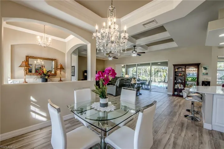 Dining space with coffered ceiling, crown molding, ceiling fan, light wood-type flooring, and beam ceiling