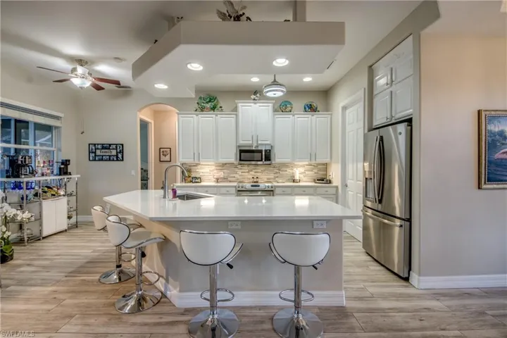 Kitchen with white cabinets, stainless steel appliances, a kitchen island with sink, and light hardwood / wood-style flooring