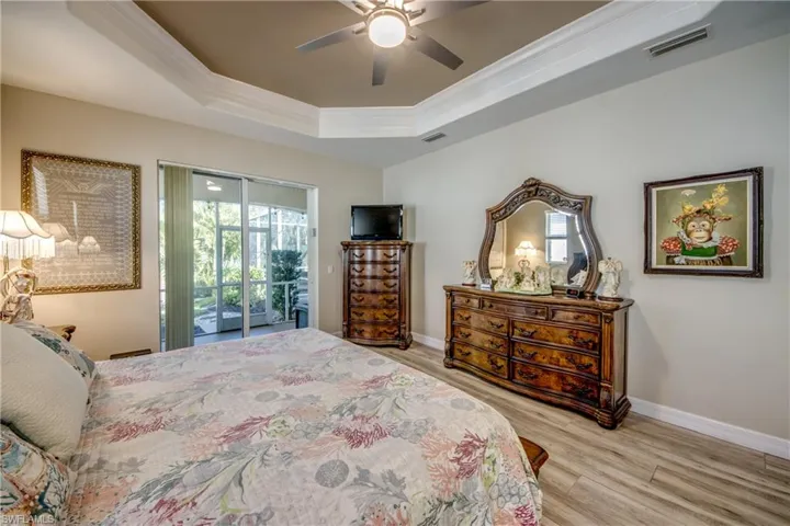 Bedroom with access to exterior, ornamental molding, a tray ceiling, ceiling fan, and light hardwood / wood-style flooring