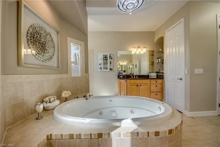 Bathroom featuring tiled tub, tile patterned flooring, and vanity