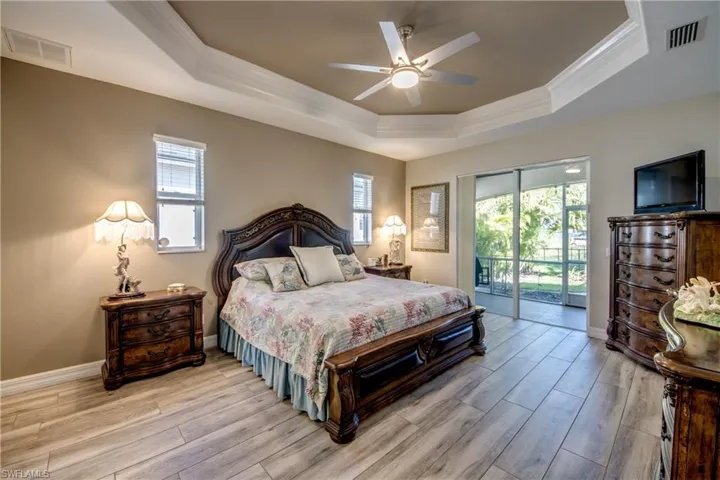Bedroom featuring a raised ceiling, access to outside, light hardwood / wood-style flooring, and ceiling fan