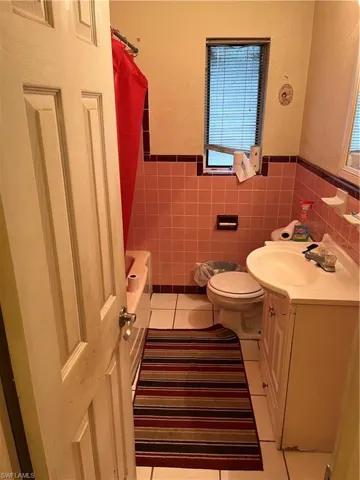 Full bathroom featuring tasteful backsplash, tile patterned flooring, vanity, toilet, and shower / bathtub combination with curtain