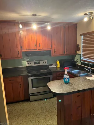 Kitchen featuring sink, stove, extractor fan, and a textured ceiling