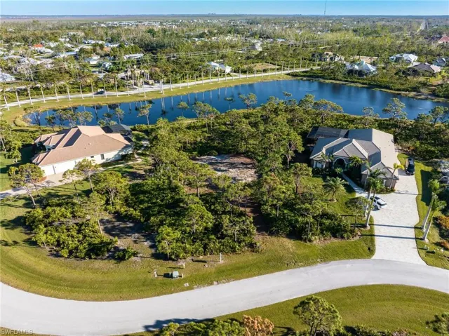 Aerial view of residential area with a nearby body of water and a tree filled landscape