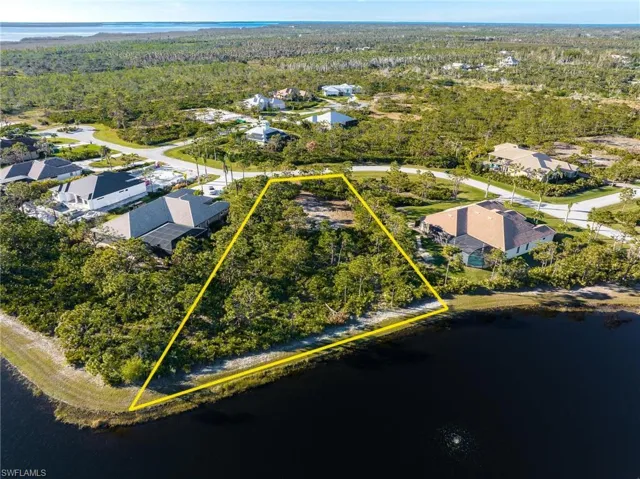 Aerial perspective of suburban area with property parcel outlined and a nearby body of water