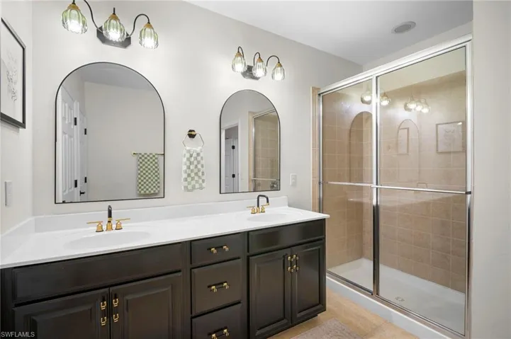 Bathroom featuring double vanity and a stall shower