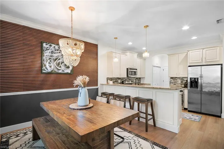 Dining room featuring arched walkways, recessed lighting, crown molding, a chandelier, and light wood-type flooring