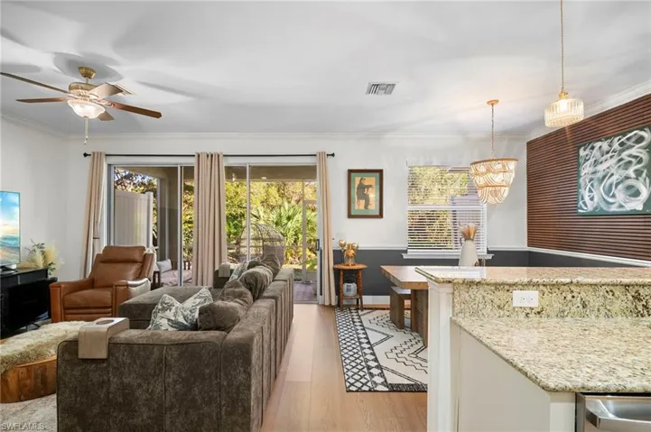Living area featuring ornamental molding, light wood-type flooring, healthy amount of natural light, and ceiling fan