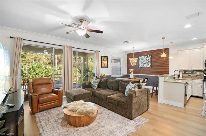 Living area with light wood-style flooring, ceiling fan, and ornamental molding