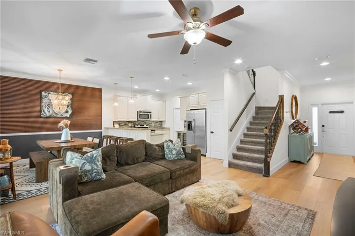 Living room with light wood-type flooring, stairway, recessed lighting, a chandelier, and ceiling fan