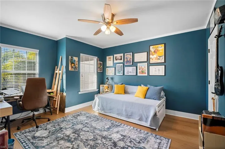 Bedroom featuring a desk, wood finished floors, ceiling fan, and crown molding