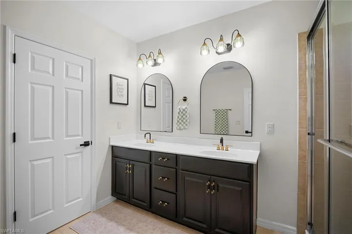 Bathroom with double vanity, a shower stall, and light tile patterned floors