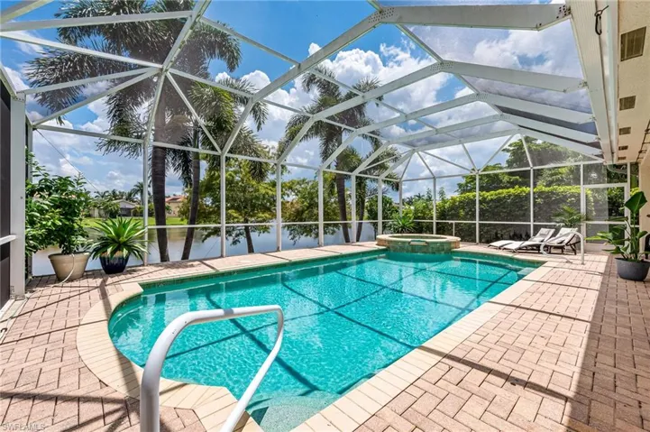 View of pool with SCREEN enclosure, an in ground hot tub, and a patio area